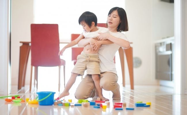 子どもに服を着せるお母さん