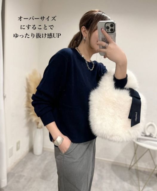 ネイビーのカシミヤクルーネックセーターを着ている