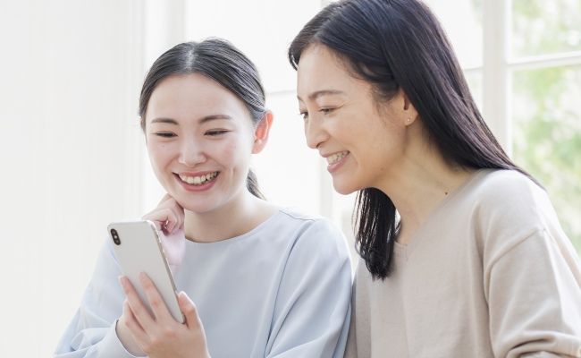 娘と一緒にスマホを見る女性のイメージ