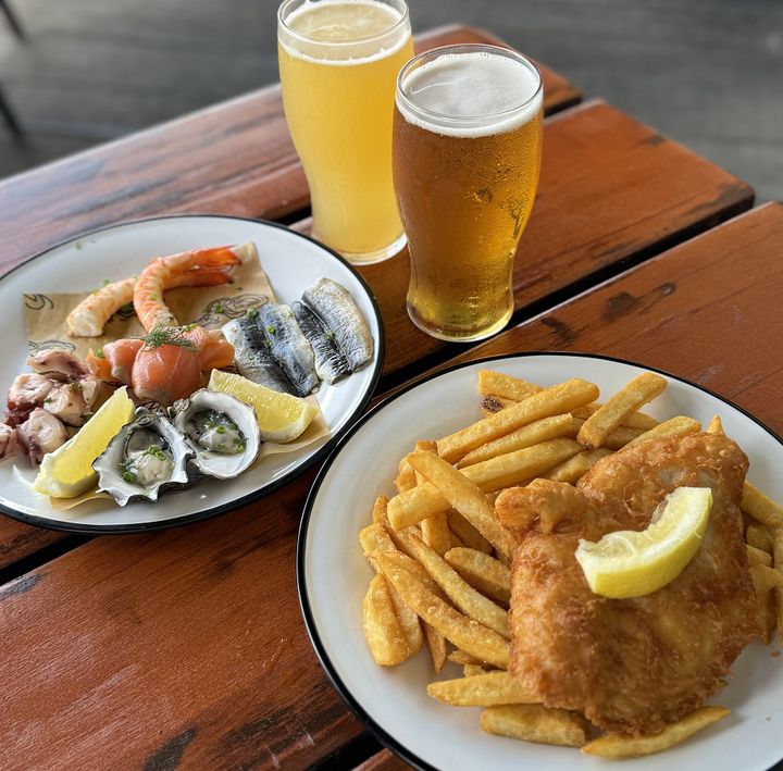 左は牡蠣やタコ、ニシンのマリネ、サーモン、海老のコールドプレート29AU$、右は伝統的なフィッシュ＆チップス17.5AU$、生ビールは12～13AU$