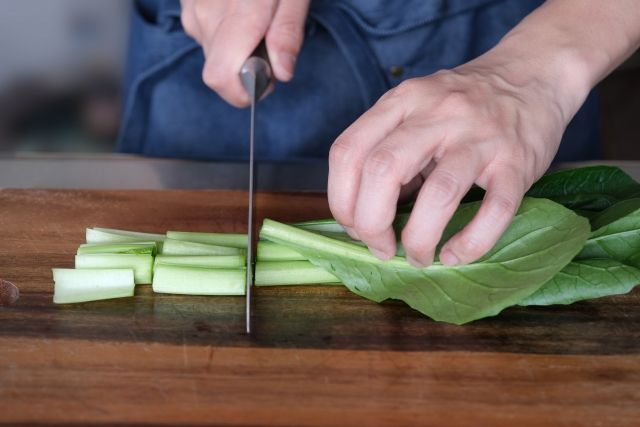 小松菜をカットする男性の手元