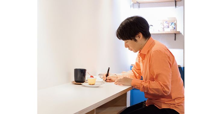 机に向かってペンを手に手紙を綴る男性