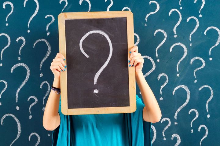 疑問符の書かれた黒板を持つ女性