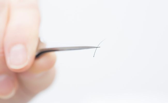 ピンセットでまつ毛を1本つまんでいるイメージ