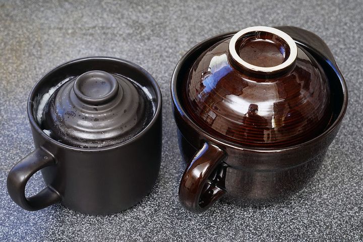 電子レンジでの加熱が終了して蒸らし状態の「炊飯マグ」と「炊飯土鍋 二重蓋」。左側の「炊飯マグ」でご飯粒が吹きこぼれているのがわかるでしょうか。