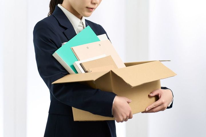 段ボールに入れた荷物を運ぶビジネスウーマン