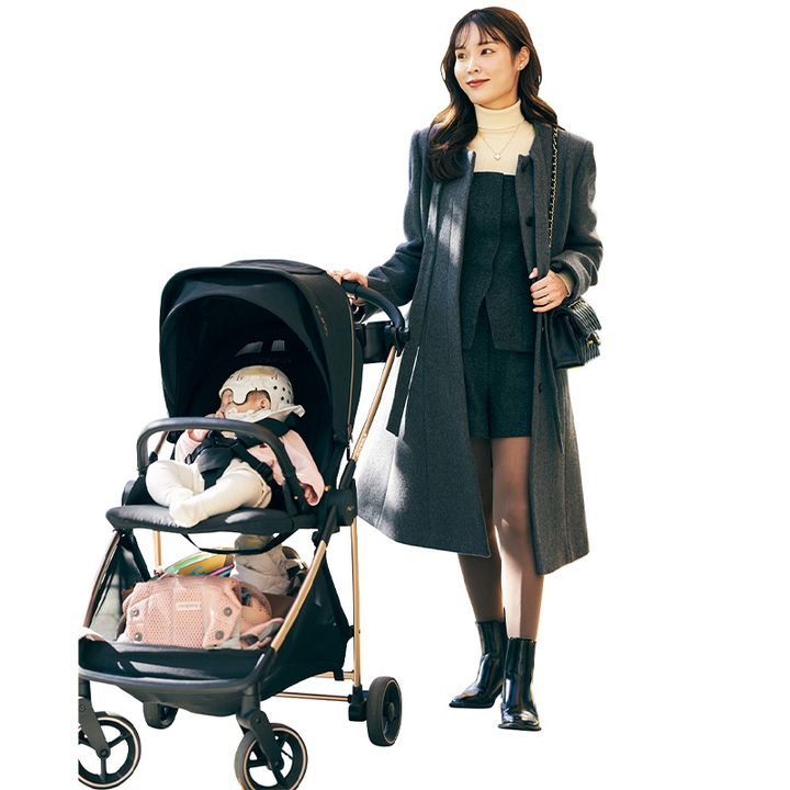 白のタートルニットに黒のショートパンツのセットアップとアウターを着てベビーカーに手を置く読者