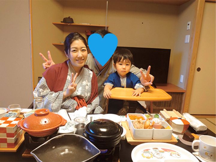 温泉宿で浴衣を着て料理を前に記念撮影をする家族