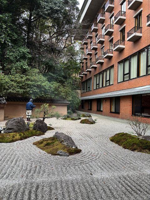 窓からの風景。庭師が枯山水庭園の砂紋を描いているところ