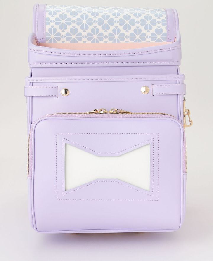 かぶせ裏にはシグニチャーのスペード柄プリントが。ボウモチーフをあしらった正面ポケットも注目。