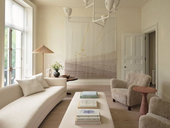 リビングルーム。右手のイージーアームチェアはフリッツ・ハンセン。左手のロングソファは、ローズ・ウニアックのウール地のカバーリングでリフォーム。窓側に置かれたエンドテーブルはジョージ・ナカシマの「ミングレンII」。花瓶はロイヤル コペンハーゲン、ボウルはクルタケスクス・オイ。石製のテーブルランプはアルベール・トルモス。フロアランプ「9602」はパーヴォ・ティネルのデザイン。アームチェアの間に置かれた「アンジェロM」シリーズのサイドテーブルはアリネア。シーリングライトはアレクサンドル・ロジェの「ニソス」。タペストリーはシモーヌ・プルーヴェの作。