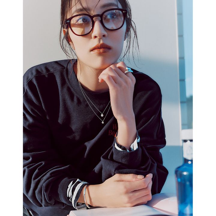 スウェットに一粒ダイヤのネックレスを2つ重ね付けしてシルバーリングとバングルと黒縁メガネをした岡本あずささん