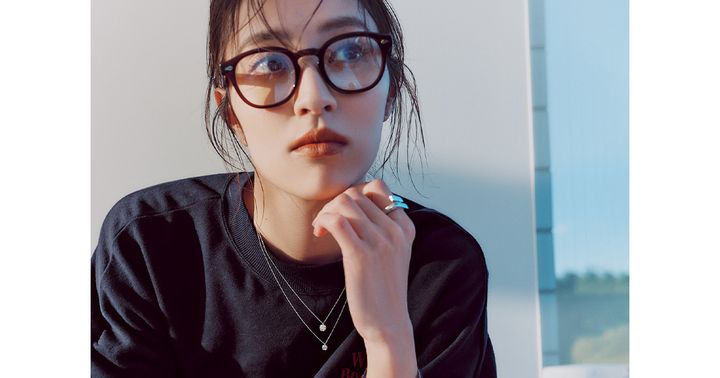 スウェットに一粒ダイヤのネックレスを2つ重ね付けしてシルバーリングと黒縁メガネをした岡本あずささん