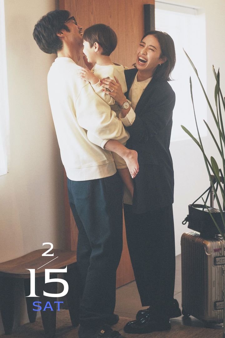 白シャツに太めのパンツのセットアップとビッグフェイスの腕時計を合わせたママと子どもを抱っこするパパ