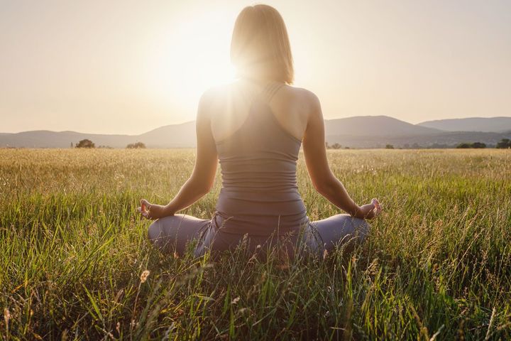 woman practices yoga and meditates in the lotus position on the field. Healthy lifestyle and Yoga concept.