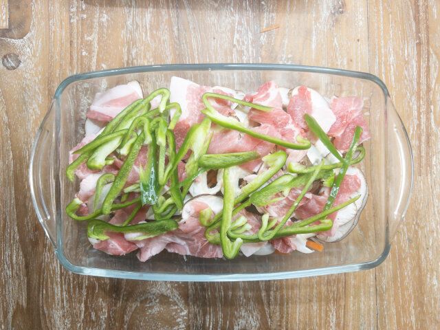 椎茸の上に豚こま切れ肉を広げて入れ、その上にピーマンを広げて入れます