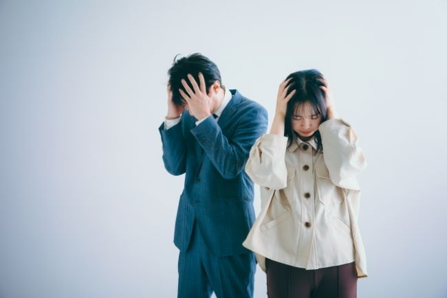 頭を抱えて悩む男女