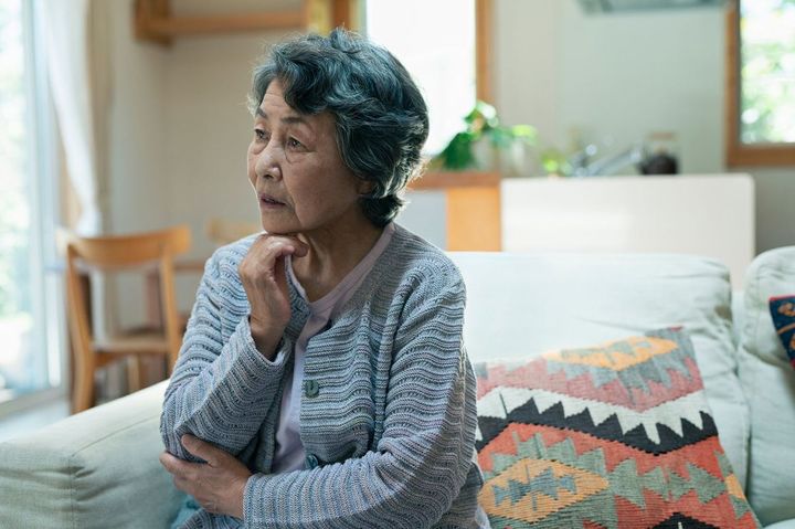 自宅で考え事をするシニア女性