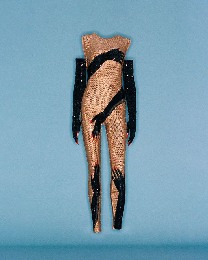 ビヨンセが2023年の「ルネッサンス・ワールド・ツアー」で着用したロエベのカスタムウェア。2022年秋冬ウィメンズコレクションから着想を得たデザインで、ゴールドクリスタルが全面に散りばめられ、錯視効果を生む手のモチーフやブラックラバーラテックスグローブが特徴的なサテンテクニカルジャージーのボディスーツ。※レプリカ（ロエベ アーカイブ）
