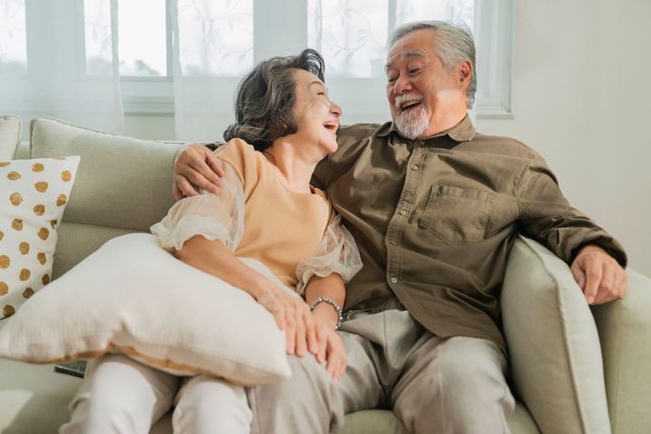 リビングルームのソファで一緒に過ごす笑顔の老夫婦