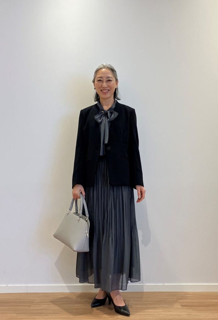 シアーボウタイブラウス GRAY ¥8,990、トリアセブレンドカラーレスジャケット BLACK ¥19,000、シアープリーツスカート GRAY ¥12,000、2WAYコンパクトバッグ GRAY ¥13,000、PLUS STYLE パンプス（ハイヒール）BLACK ¥11,000／すべてプラステ