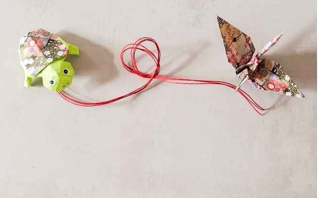 赤い糸で結ばれた折り紙の鶴と亀