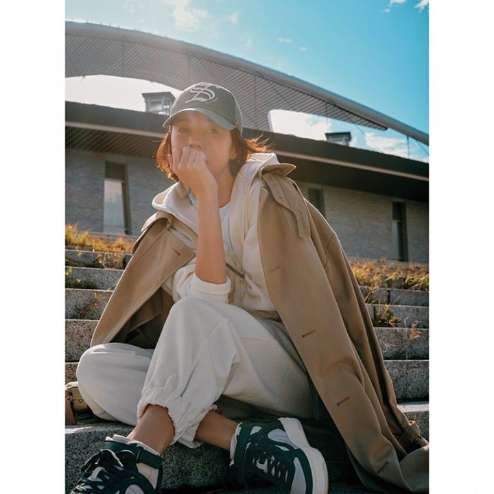 オフホワイトフーディにスウェット、キャップのカジュアルさにベージュトレンチ