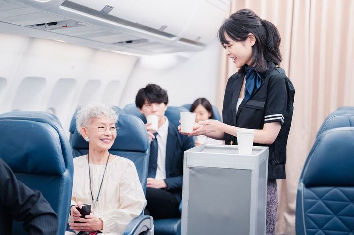 飛行機の機内で飲み物を提供する客室乗務員