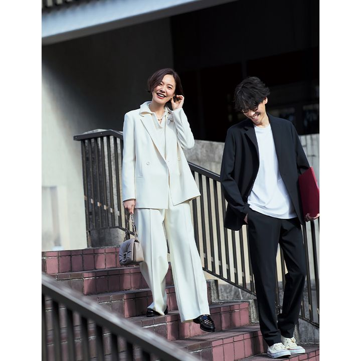 オフホワイトのパンツスーツのインにポロニットを着たママとラフなジャケパンスタイルのパパ