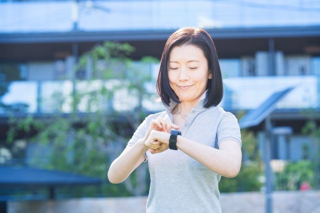 腕時計を見る、外で運動している女性