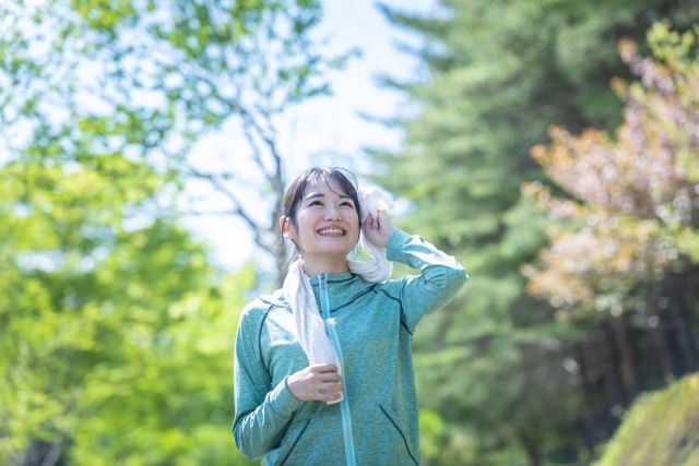 外で運動をする女性 汗を拭く