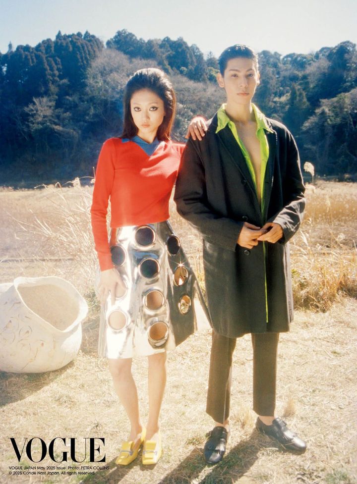 バック・トゥ・ザ・フューチャー<br /> 襟もとに青の差し色でコントラストをつけた鮮烈な赤のトップに、大胆にいくつも円形をくりぬいたシルバーのスカートを合わせたプラダ。1960年代の雰囲気を纏いながらもそこに感じられる近未来感、そして違和感が生むアンサンブルの面白さが、ファッションの無限の可能性を描き出す。<br /> 〈Raul〉黒のコート ¥693,000 緑のコート ¥319,000 パンツ（参考色） ¥363,000 シューズ ¥225,500（すべて予定価格） 〈Mona〉トップ ショーツ ともに参考商品 スカート ¥1,265,000 シューズ（参考色） ¥214,500（ともに予定価格）／ すべてPRADA（プラダ クライアントサービス）