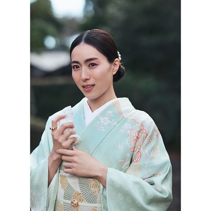 淡いグリーン系の着物に組み紐の帯留めを合わせた笹川友里さん