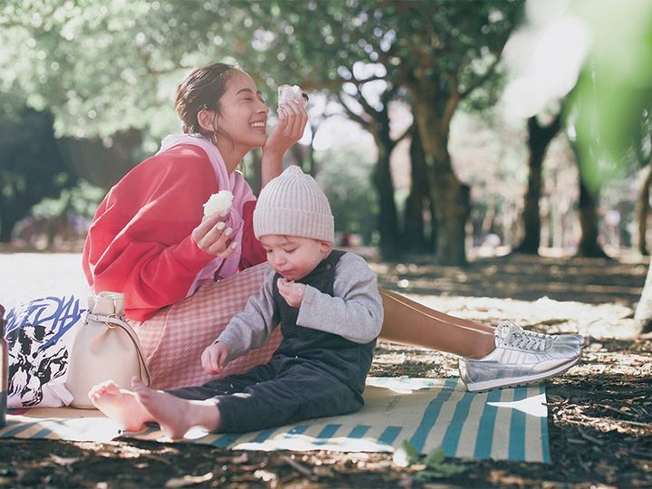 スウェットにピンクのニットを肩掛けしてピンクのギンガムチェックのスカートとシルバーのスニーカーを合わせた着こなし