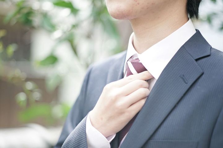 ネクタイに手を置くスーツを着たビジネスマン