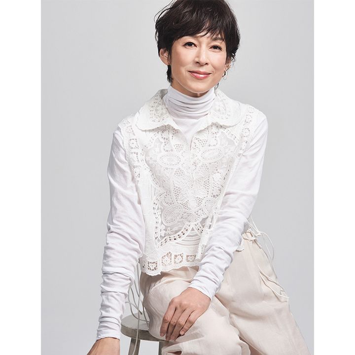白のタートルトップスにレースのブラウスを重ねて白のパンツを合わせた鈴木保奈美さん