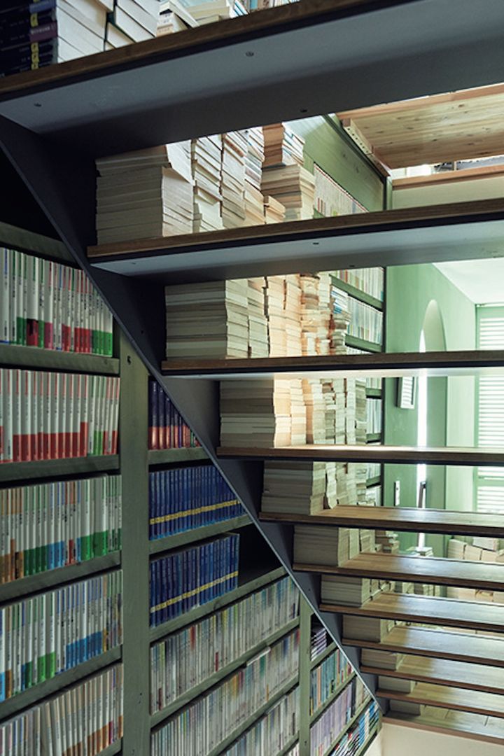 美しいグリーンに塗られた文庫用書棚が階段室の壁を埋める