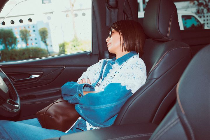 デニムの上下にレースのカラーをつけて車の中で昼寝する東原亜希さん