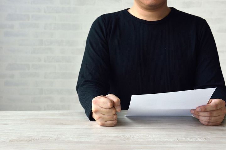 書類を見ながら怒る男性