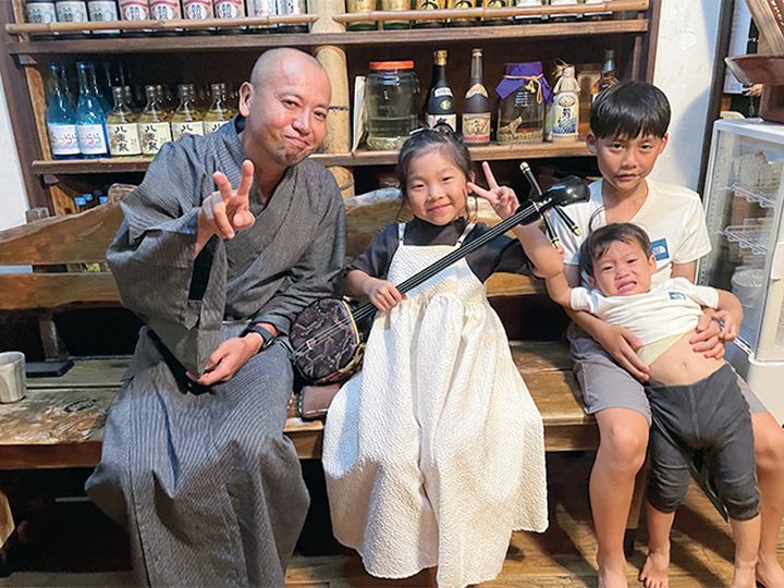 石垣島の『舟蔵の里』の郷土料理棟で三線を手に記念撮影する子どもたち