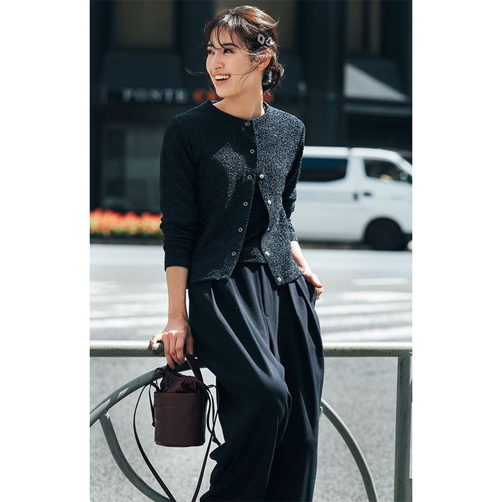 ラメ素材のカーデアンサンブルニットに、ゆるっとしたシルエットの暗色パンツを合わせた