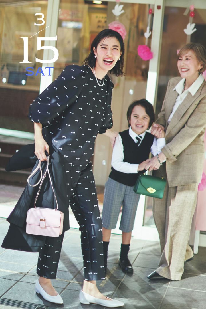 リボンツイードのパンツセットアップにパールジュエリーやピンクのバッグを合わせたママとフォーマルコーデの息子と祖母