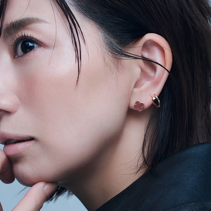 左耳にヴァンクリーフ＆アーペルのカーネリアンのスウィートアルハンブラとカルティエのジュストアンクルのシングルフープピアスを2個付けした東原亜希さん