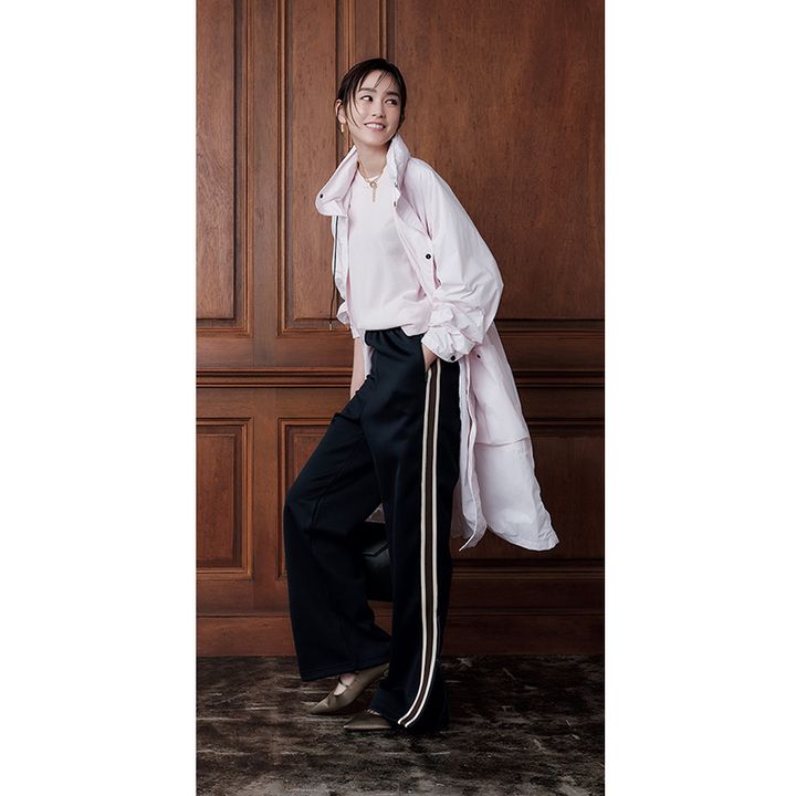 ピンクのニットとアウターにネイビーベースにボルドーのラインが入ったウーアのトラックパンツを合わせた着こなし