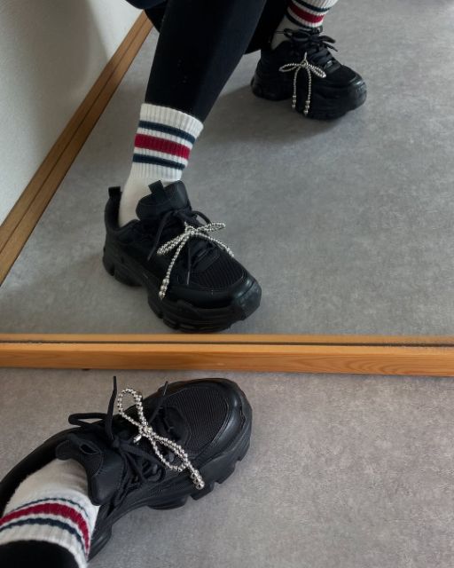 黒のシルバーリボンモチーフチャームを履いている