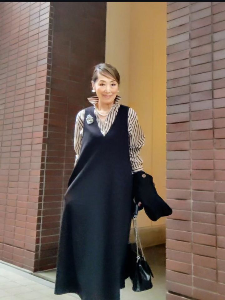 Vネックのブラックワンピースの下にシャツを重ねたコーデ