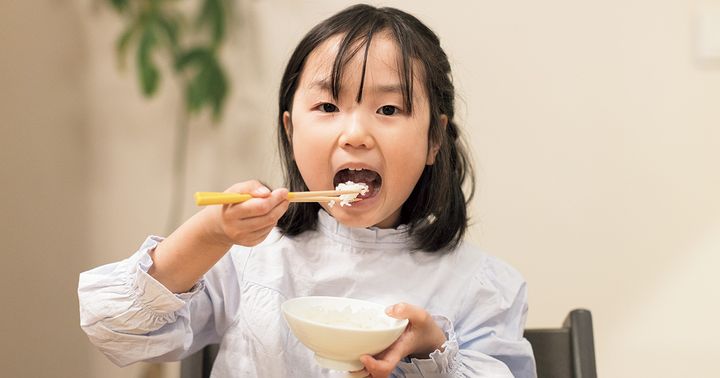 お箸を上手に使ってご飯を食べる女の子