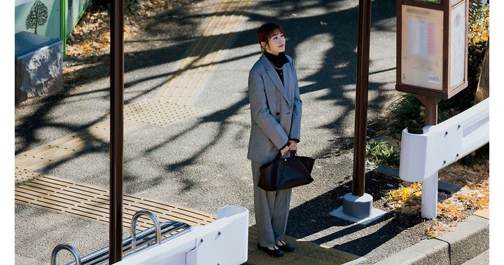 グレーのスーツにザ・ロウの横長のキャンバストートとフラットシューズを合わせた桐谷美玲さん