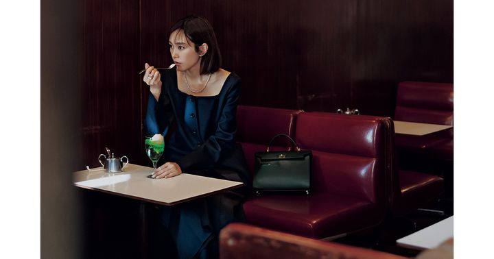ネイビーのセットアップを着てメロンソーダを食べる桐谷美玲さんと傍らに置かれたアニヤ・ハインドマーチのハンドバッグ