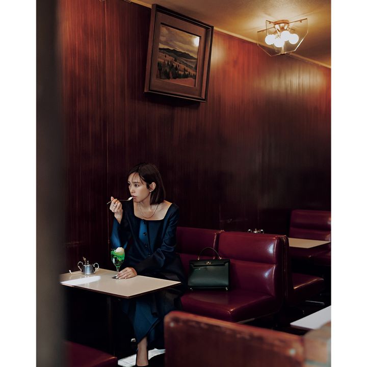 ネイビーのセットアップを着てメロンソーダを食べる桐谷美玲さんと傍らに置かれたアニヤ・ハインドマーチのハンドバッグ